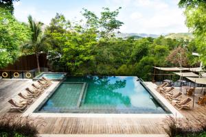 an infinity pool with chairs and a table and trees at The Funny Lion in Coron