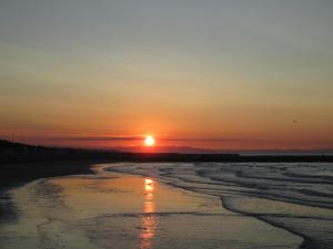 a sunset on the beach with the sun setting at Hotel Berna in Eraclea Mare