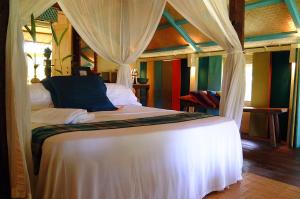 a bedroom with a white bed with a canopy at Bon Ton Antique Wooden Villas in Pantai Cenang +52 photos