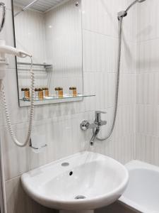 a white bathroom with a sink and a shower at Dvina Hotel in Velikiy Ustyug