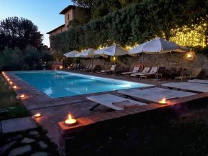 a swimming pool with candles and umbrellas at night at Villa Il Poggiale Dimora Storica in San Casciano in Val di Pesa