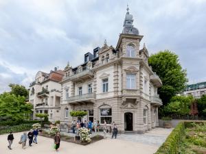 personas caminando frente a un gran edificio blanco en Hotel Villa Grunewald en Bad Nauheim