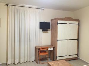 TeanoにあるLe Quattro Stagioniのデスク、テレビ、カーテンが備わる客室です。