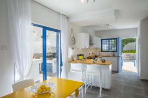 a kitchen with white cabinets and a yellow table at Protaras Villa Loulla in Protaras