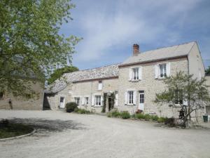 a stone house with a driveway in front of it at Ferme de La poterie in Donnery