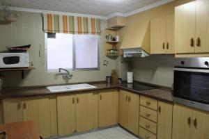 cocina con armarios de madera, fregadero y microondas en Piso Colon, en Paiporta
