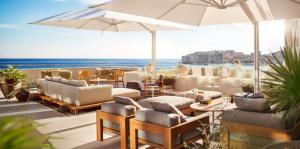 a patio with chairs and tables and an umbrella at Hotel Excelsior in Dubrovnik