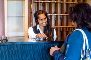 a woman sitting at a counter talking to a waitress at Hotel Utsikten - by Classic Norway Hotels in Geiranger