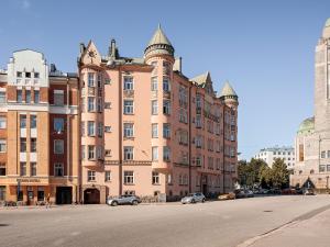 un grand bâtiment avec des voitures garées devant lui dans l'établissement Artist Apartment Susi, à Helsinki