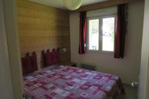 a bedroom with a bed with a red blanket and a window at Apartment Location Les balcons de La Mauselaine in Gérardmer