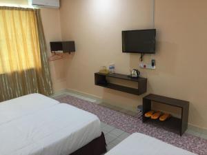 a hotel room with two beds and a flat screen tv at Indah Inn in Tawau