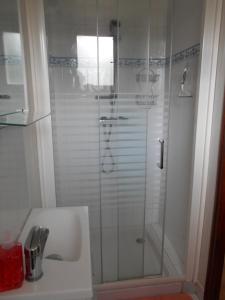 a shower with a glass door next to a sink at Fée Morgane - Chambres in Saint-Coulomb