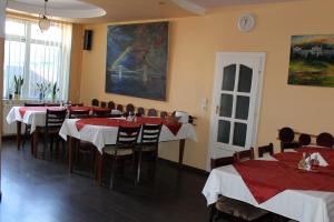 a dining room with tables and chairs and a painting on the wall at Pension Tip-Top in Târgu-Mureş