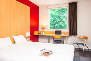 a bedroom with a bed and a desk with a laptop at B&B HOTEL La Rochelle Centre in La Rochelle