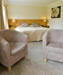 a bedroom with a bed and two chairs at Edenhall Country Hotel in Penrith