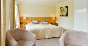 a bedroom with a bed and two chairs at Edenhall Country Hotel in Penrith