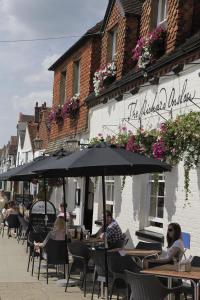 un gruppo di persone seduti ai tavoli sotto un ombrello di The Richard Onslow a Cranleigh