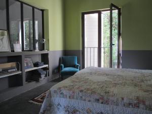 een slaapkamer met een bed, een stoel en een raam bij Maison Itzé in Saint-Saturnin-dʼApt