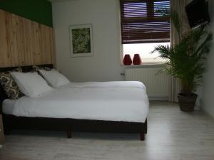 a bedroom with a large white bed and a plant at Logement-B&B Safier in Joure