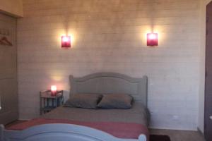 a bedroom with two lights on the wall and a bed at Chambres Aux Bonnes Herbes in Bais