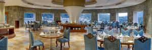 a restaurant with tables and chairs in a room withwindows at Raajsa Resort Kumbhalgarh in Kumbhalgarh