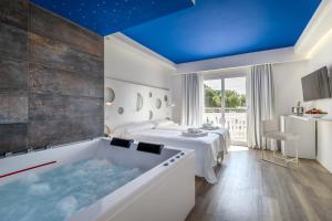 łazienka z wanną i łóżkiem w obiekcie Welikehotel Triton Beach w Cala Ratjada