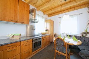 a kitchen with wooden cabinets and a table and a couch at Greenhome Appartement in Niedernsill