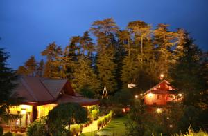 una casa con jardín frente a un bosque en The Chalets Naldehra en Shimla