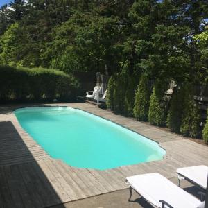 una gran piscina azul con 2 bancos blancos en un patio en Jardine's Inn, en Rexton