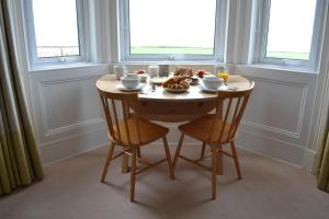 a table with a bowl of food and two chairs at Burnside Farm B & B in Girvan