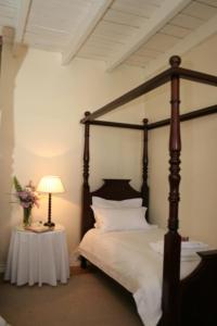 a bedroom with a canopy bed with a table with a lamp at De Kothuize 16 in Graaff-Reinet