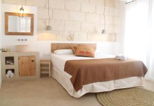 a white bedroom with a bed and a mirror at S'Esparteria Hotel in Ciutadella