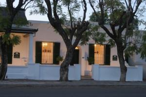 a white house with two trees in front of it at De Kothuize 16 in Graaff-Reinet
