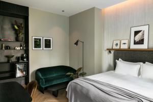 a bedroom with a bed and a green chair at Hôtel National Des Arts et Métiers in Paris