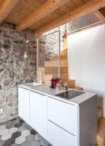 a kitchen with white cabinets and a stone wall at La Casa Della Zia in Sarnico