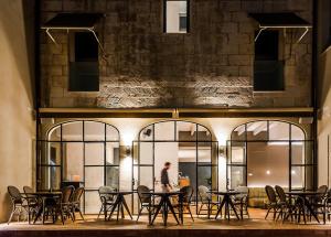 un homme marchant devant un bâtiment avec des tables et des chaises dans l'établissement Bordoy Casa Ládico - Hotel Boutique Adults Only, à Port Mahon