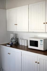 a kitchen with white cabinets and a microwave on a counter at De Kothuize 16 in Graaff-Reinet