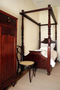a bedroom with a bed with a wooden frame and a chair at De Kothuize 16 in Graaff-Reinet