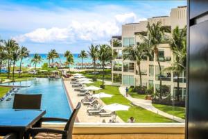 a view of a resort with a pool and palm trees at The Elements Oceanfront & Beachside Condo Hotel in Playa del Carmen