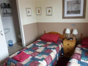 a bedroom with two beds with red pillows at The Crouch Oak in Addlestone