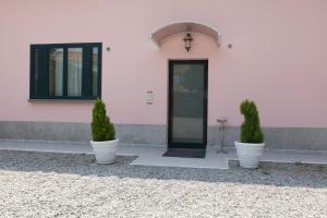 una casa rosa con due piante in vaso davanti di Affittacamere Europa Fiera a Rho