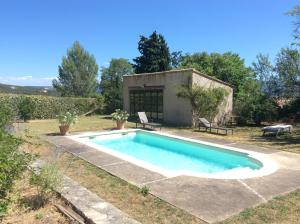 a pool in the yard of a house with two benches at Maison Itzé in Saint-Saturnin-lès-Apt