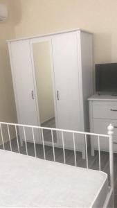 アグローポリにあるIl Rifugio Di Vincenzoの白いキャビネット、ベッド、テレビが備わるベッドルーム1室が備わります。