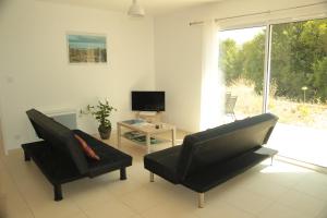 a living room with two black chairs and a television at Entre Brousse Et Garrigue in Viols-le-Fort