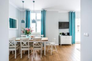 a dining room with blue curtains and a table and chairs at Sanhaus Apartments - Parkowa 44 in Sopot