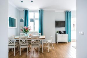 ソポトにあるSanhaus Apartments - Parkowa 44のダイニングルーム(青いカーテン、テーブル、椅子付)