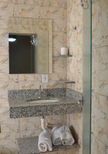a bathroom with a sink and a mirror and towels at Telma Hotel in Bauru