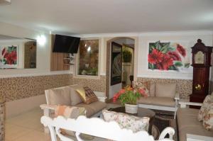 a living room with two couches and a clock at Telma Hotel in Bauru