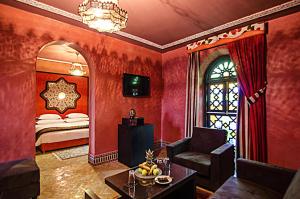 een woonkamer met rode muren en een bed met een raam bij Palais Ommeyad Suites & Spa in Fès