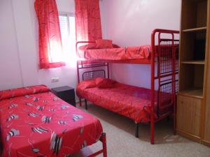 マタラスカニャスにあるApartamento Virgen de la Sierraの二段ベッド2台と赤いベッド1台が備わる客室です。 +3枚の写真
